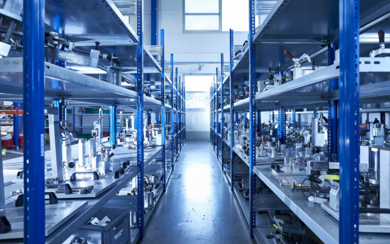 Regalgang mit zahlreichen metallischen Spann- und Montagevorrichtungen aus dem Vorrichtungsbau in der Werkhalle