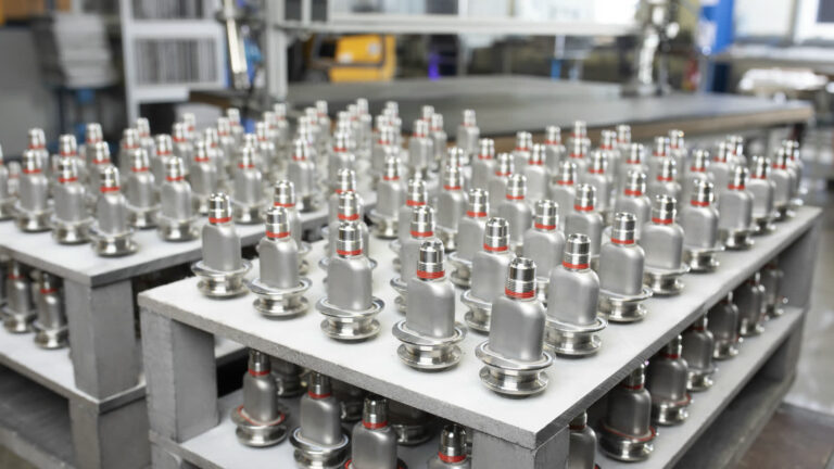 Reihen polierter Edelstahl-Bauteile mit roten Dichtringen für Vakuum- und Messtechnik in der Fertigung