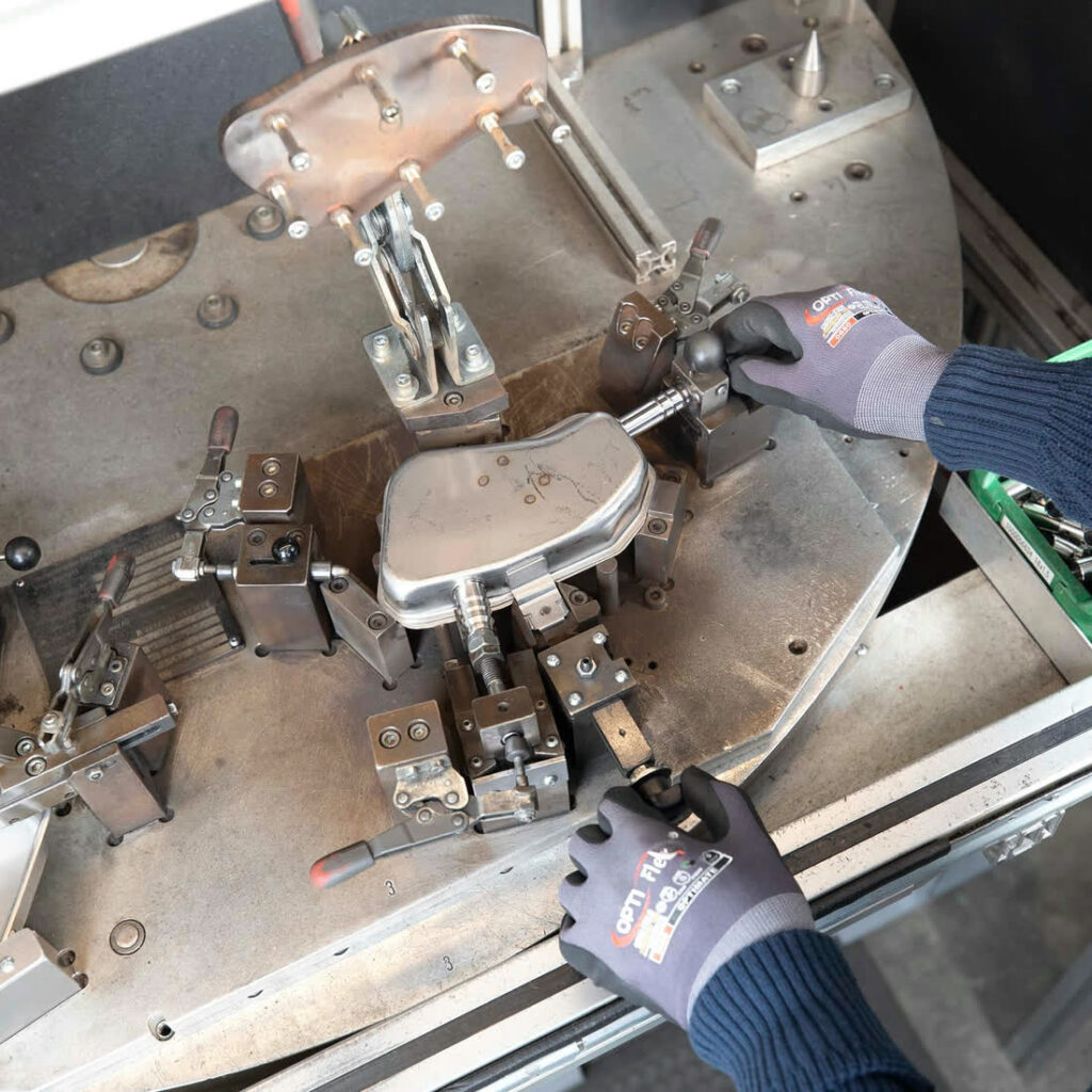 Edelstahlbauteile in Spannvorrichtung fixiert, Hände richten Teile fürs Vakuumlöten mit Kniehebelspannern aus